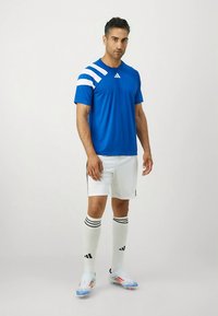 Sinine spordisärk valgete triipudega, valgete lühikeste pükste ja põlveni ulatuvate sokkidega, millel on mustad triibud, kantud mehe poolt.