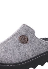Grå slip-on klump med rund tå, texturerad yta och en brun cirkulär logotypmärke; har en svart gummisula med grep.