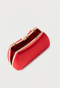 Pochette en satin rouge avec cadre en métal doré et fermoir en perle, partiellement ouverte montrant l'intérieur et l'étiquette du créateur "Anna Field".
