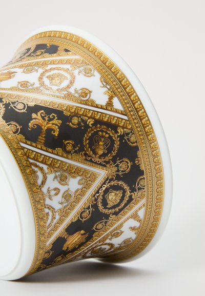 Xícara de porcelana com padrão barroco detalhado em preto e dourado, apresentando motivos decorativos intrincados e realces texturais.