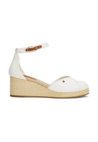 Witte canvas wedge schoen met een geweven jute hak, enkelband met bruine leren accenten en een klein logo aan de zijkant.