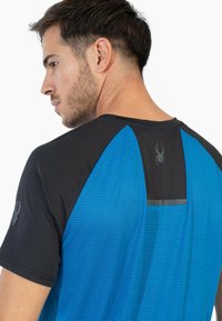 Camisa atlética para hombre con una combinación de colores en azul y negro, tejido texturizado, mangas cortas y un detalle reflectante en la parte trasera.