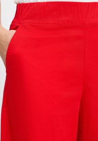 Rode, lichte stoffen broek met een elastische tailleband, zijzakken en een gladde textuur, met een eenvoudig, recht model.