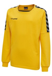 Gul långärmad sweatshirt i mjukt tyg, med rund halsringning, svarta chevronmönster på axlarna och logotyp på bröstet.