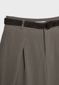 Prilagojeni sivi hlače iz gladke tkanine, z žepi na sprednji strani, ravnim pasom in temnim semisuhim pasom z kovinsko spono.