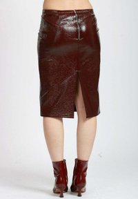 Gonna a matita in ecopelle bordeaux con spacco posteriore, chiusura con zip e una finitura elegante. La gonna è di lunghezza al ginocchio, con una silhouette aderente.