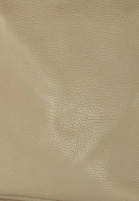 Beige leer met een textuur, dat een zachte, gekreukelde uitstraling vertoont. Het materiaal heeft een subtiele glans en een fijne korrelpatroon.