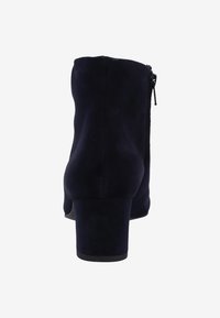 Botas de tobillo de ante en azul marino oscuro con puntera redondeada, cremallera en la parte trasera y tacón grueso. Textura suave con una silueta sólida.