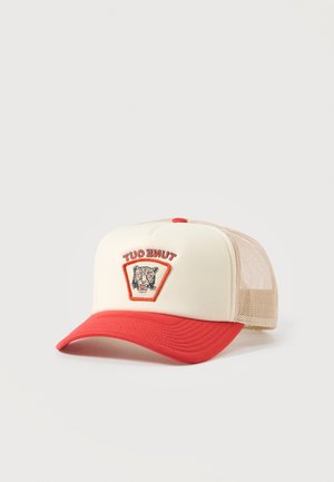 Șapcă trucker bej și roșie cu partea din spate din plasă, vizieră curbată roșie și un patch brodat cu capul unui leopard și textul „TUNE OUT”.