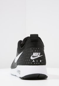 Svart Nike Air-sneaker med perforerat överdel, vit swoosh-logotyp, vadderad krage och vit dämpad sula.