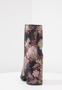 Bottine noire avec un motif floral aux tons roses et dorés, dotée d'un talon épais et d'une texture lisse. Coutures détaillées visibles.
