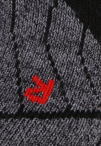 Berretto grigio lavorato a maglia con un motivo testurizzato, logo ricamato rosso sul davanti e dettagli neri.