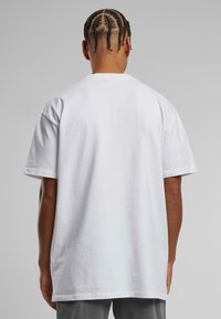 Hvid bomulds T-shirt med korte ærmer, afslappet pasform og en blød tekstur, med et ensfarvet design på bagsiden og rund hals.