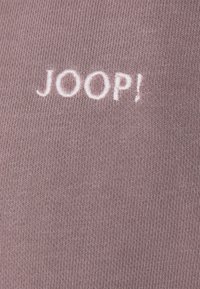 Tessuto a coste rosa con una consistenza morbida, presenta un logo ricamato "JOOP!" in rosa chiaro, centrato sul materiale.