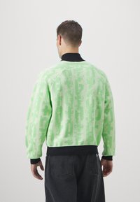 Maglione verde a maglia con un motivo testurizzato, colletto e polsini neri a coste, caratterizzato da una vestibilità rilassata e spalle scese.