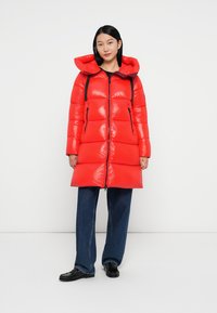 Rote Puffjacke mit glänzender Oberfläche, Kapuze und kontrastierenden schwarzen Reißverschlüssen. Verfügt über horizontale Steppnähte und ein mittellanges Design.