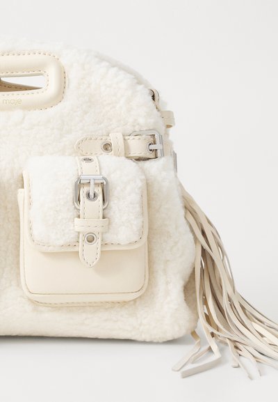 Borsa in shearling bianco con tasca frontale in pelle, hardware in argento e lunghe frange in pelle. Forma arrotondata e manico superiore.