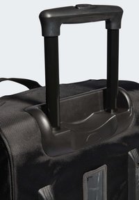 Borsa da viaggio nera in nylon con manico telescopico nero, caratterizzata da un tessuto testurizzato e una base in plastica con pulsante a pressione circolare.