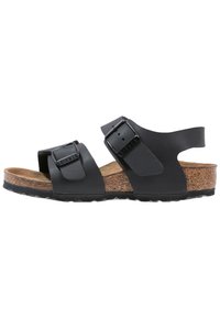 Svart sandal med två justerbara remmar, korkfotbädd och texturerad gummisula. Utrustad med metallspännen och en mjuk läderöverdela.