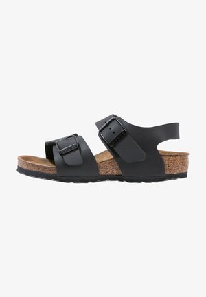 Sandal nero con due cinturini regolabili, sottopiede in sughero e suola in gomma testurizzata. Presenta fibbie in metallo e una parte superiore in morbida pelle.