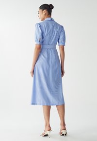 Robe rayée bleu clair avec une taille cintrée, de courtes manches bouffantes et un col. Le matériau semble lisse, avec un design midi.