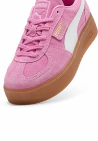 Růžové semišové tenisky Puma Palermo s bílým pruhem, růžovými tkaničkami a gumovou podrážkou, zobrazující boční a horní detaily.