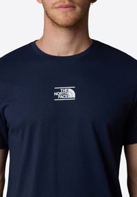 Marineblå t-shirt med korte ærmer lavet af bomuld, med et hvidt logo print af et bjergdesign på venstre bryst.