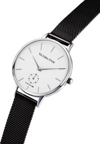Orologio argento con quadrante bianco, indicatori delle ore minimalisti e una piccola lancetta dei secondi. Presenta un bracciale in rete nera e il logo "Victoria-Hyde."