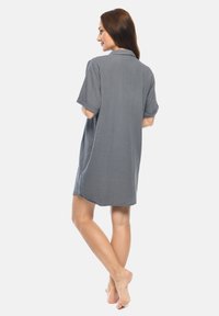 Gray, short-sleeved shirt dress with a collar, featuring a textured fabric, loose fit, and side slits for ease of movement.