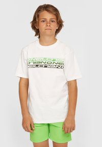 Witte katoenen T-shirt met meerkleurige tekst (groen, zwart) op de borst; gecombineerd met felgroene shorts. Casual fit, ronde halsontwerp.