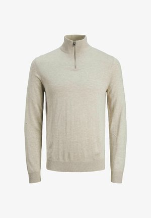 Beżowy sweter na zamek, szare spodni w pasy i beżowe trampki. Prosty design, miękka tekstura i neutralne kolory. Minimalistyczny styl.