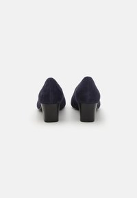 Talons en daim bleu marine avec un bout arrondi et un talon carré noir de hauteur intermédiaire. Texture lisse, design minimaliste, aucune accentuation ou motif visible.