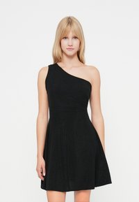Rochie neagră cu un singur umăr, cu un corset ajustat și fustă evazată. Confecționată dintr-un material texturat, are o siluetă fluidă și detalii minime.
