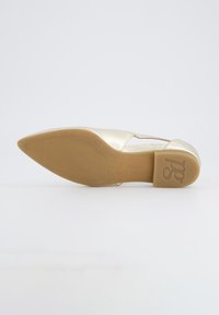 Zlatá kožená balerína s špičatou špičkou, s výřezovým designem a světle hnědou gumovou podrážkou. Logo vytištěné na podrážce.