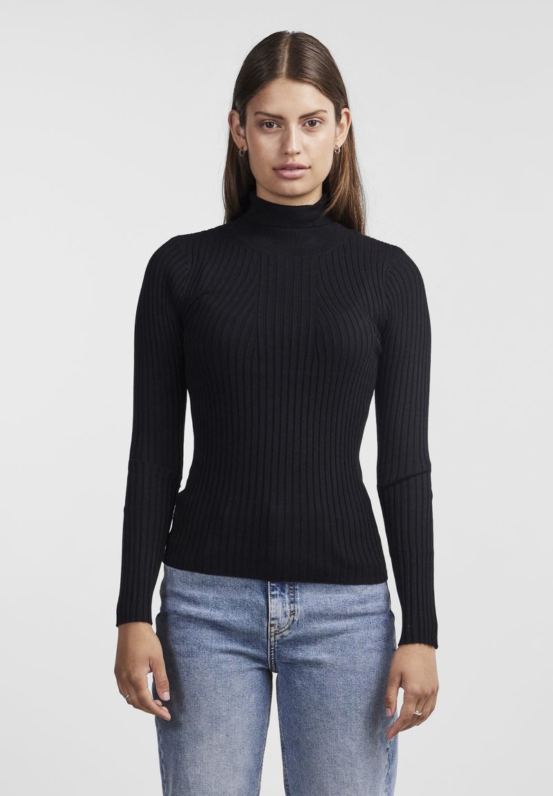 Pull en maille côtelée noir avec col roulé, à manches longues, design ajusté et texture douce, assorti à un jean en denim bleu clair.