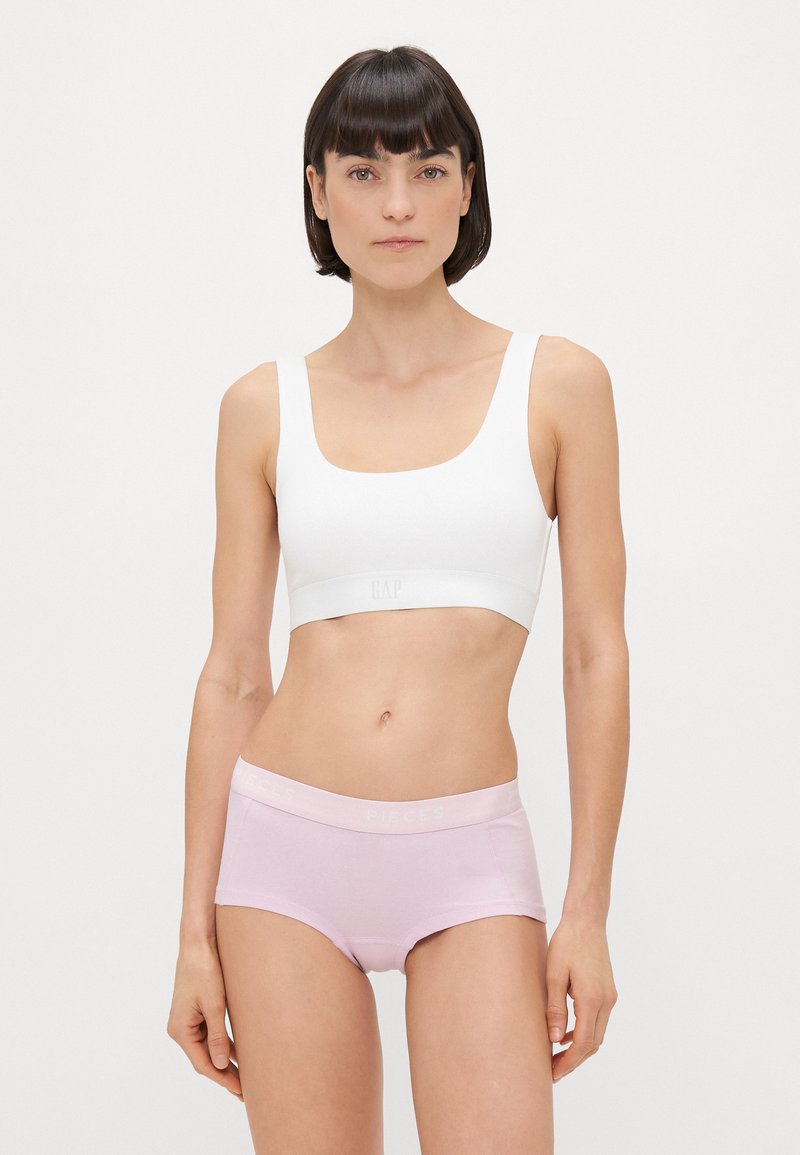 Λευκό bralette με φαρδιές τιράντες και λογότυπο στη ζώνη. Ανοιχτό μωβ boyshorts με αντίθεση στη ζώνη με το λογότυπο. Λείος ύφασμα και εφαρμοστή σχεδίαση.