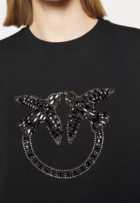 Felpa nera con un design circolare raffigurante due uccelli impreziositi, decorati con strass neri e argentati per conferire texture e dettagli.