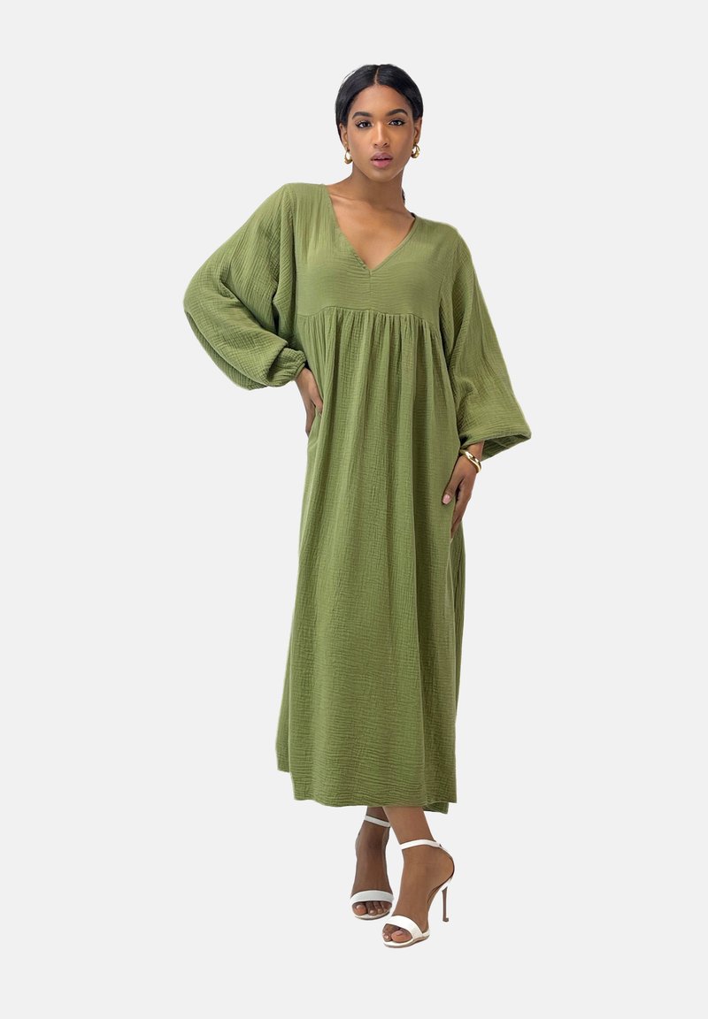 Langes, grünes Kleid aus strukturiertem Stoff mit V-Ausschnitt und Ballonärmeln, das einen gerafften Oberteil und einen fließenden Schnitt aufweist.