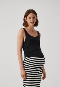 Fekete ujjatlan felső széles pántokkal, párosítva egy csíkos fekete-fehér testhez simuló kismama szoknyával, amely kiemeli az alakot.