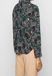 Langsleeve shirt in donkergroene stof met een zwart-wit dierenprint, met een gestructureerde kraag en een gebogen zoom.