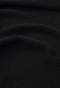 Schwarzer Wollstoff mit einer weichen, strukturierten Oberfläche, der sanfte Falten und Drapierungen zeigt und eine glatte, fließende Qualität veranschaulicht.