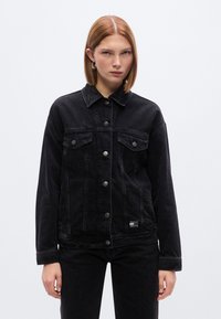 Μαύρο τζιν μ πουφάν με κούμπωμα με κουμπιά, τσέπες στο στήθος και γιακά. Διαθέτει άνετη εφαρμογή και μικρό λογότυπο κοντά στο κάτω μέρος.