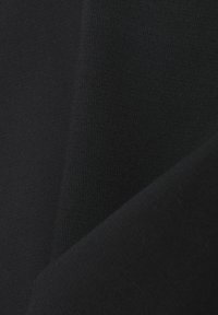 Nahaufnahme von glattem schwarzem Stoff mit feiner Textur und sanften Falten, die weiche Schatten erzeugen.