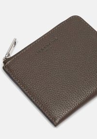 Portefeuille en cuir marron à fermeture éclair avec une surface texturée, doté de quincaillerie en argent et d'un logo embossé sur le devant. Forme rectangulaire.