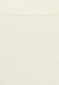 Texture côtelée dans une teinte crème clair, mettant en valeur un tissu lisse et doux avec une apparence légèrement extensible. Pas de motifs ou accents notables.