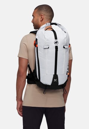 White and black plaid backpack with adjustable straps, orange hardware accents, and a roll-top design. Features branding on the front.