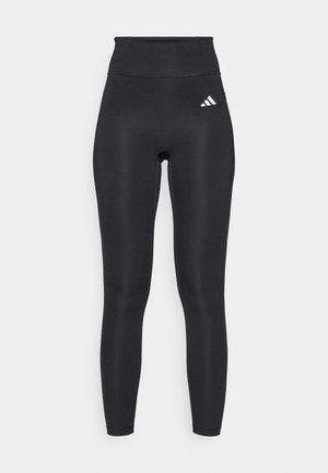 Leggings atléticos negros de tiro alto, hechos de material elástico, con una textura suave y un pequeño logo blanco cerca de la cintura.