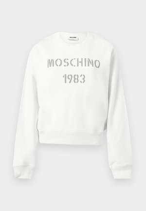 Hvid crewneck-sweatshirt med lange ærmer, ribbet manchetter og kant, med "MOSCHINO 1983" i grå stencil-stil tekst på forsiden.