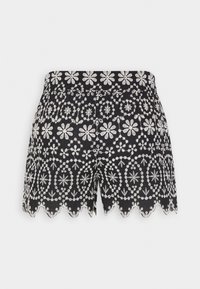 Zwarte shorts met witte bloemen en geometrische borduursels en een gegolfde zoom tegen een effen witte achtergrond.