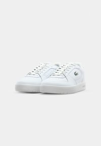 Witte leren sneakers met ronde neuzen, platte veters, geperforeerde details en een rubbere zool. Beschikt over een groen logo aan de zijkant.